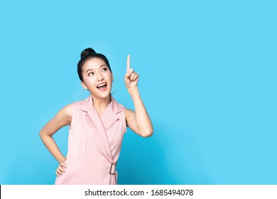 Portrait of Asian beautiful young woman pointing up one hand with finger on upper side with smile face. The pretty girl stand and looking at camera in studio. Advertisement & presentation concept.