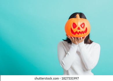 Portrait Of Asian Beautiful Young Woman Holding Orange Model Pumpkins At Her Head, Funny Happy Female With Ghost Pumpkins, Studio Shot Isolated On Blue Background