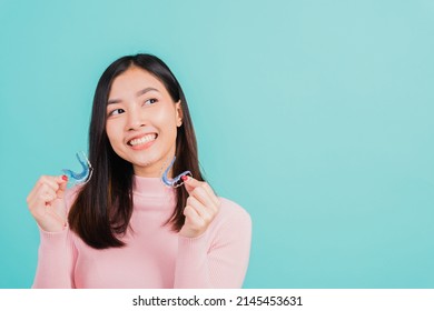 Portrait Asian beautiful young woman smiling hold silicone orthodontic retainers for teeth, Teeth retaining tools after removable braces, isolated blue background, Dental hygiene healthy care concept - Shutterstock ID 2145453631