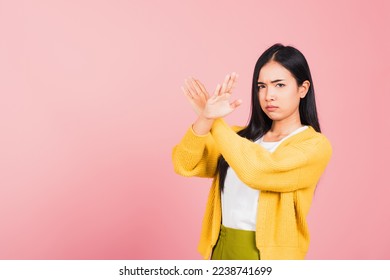 Portrait Asian beautiful young woman unhappy or confident standing wear holding two cross arms say no X sign, studio shot isolated pink background, Thai female pose reject gesture with copy space - Powered by Shutterstock