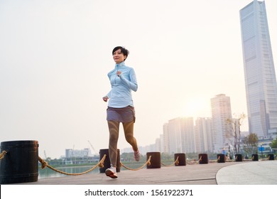 Portrait Of Asian Beauty Jogging In City Park At Sunset