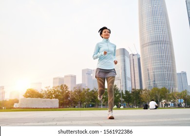 Portrait Of Asian Beauty Jogging In City Park At Sunset