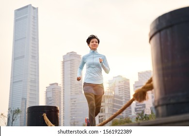 Portrait Of Asian Beauty Jogging In City Park At Sunset