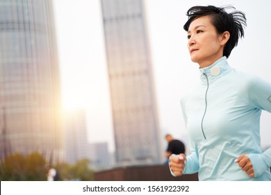 Portrait Of Asian Beauty Jogging In City Park At Sunset