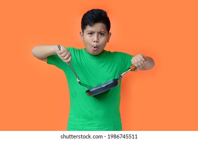 portrait of asian boy with expression holding cooking utensil