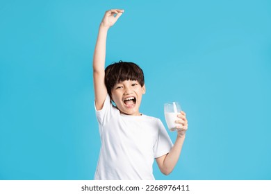 Portrait of asian boy holding cup of milk, isolated on blue background - Powered by Shutterstock