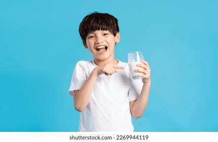 Portrait of asian boy holding cup of milk, isolated on blue background - Powered by Shutterstock