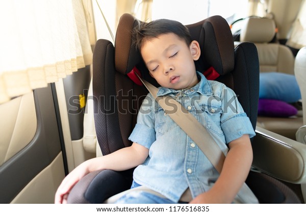 Portrait of asian\
boy wearing jean shirt sleeping in car seat, image with toning and\
effect of soft shining\
sun