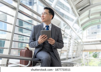 Portrait asian business man on business district ,senior visionary executives leader with business vision , tabled phone computer in hand - lifestyle business people concept