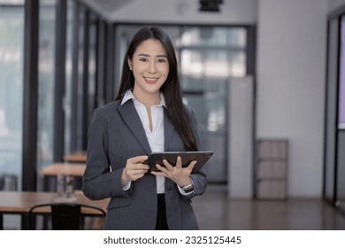 Portrait of asian business woman holding a digital tablet and standing in creative office, Successful businesswoman. - Powered by Shutterstock