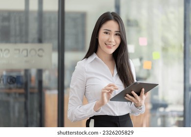 Portrait of asian business woman holding a digital tablet and standing in creative office, Successful businesswoman. - Powered by Shutterstock