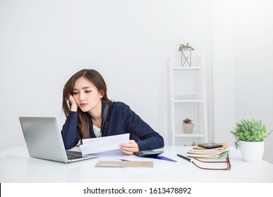 Portrait Of Asian Business Woman Paying Bills Online With Laptop In Office. Beautiful Girl With Computer And Chequebook, Stressful Bankruptcy Paying Bills. Startup Business Financial Account Concept