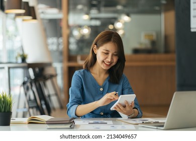 Portrait of asian business woman paying bills online with laptop in office. Beautiful girl with computer and chequebook, happy paying bills. Startup business financial calculate account concept