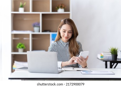 Portrait Of Asian Business Woman Paying Bills Online With Laptop In Office. Beautiful Girl With Computer And Chequebook, Happy Paying Bills. Startup Business Financial Calculate Account Concept