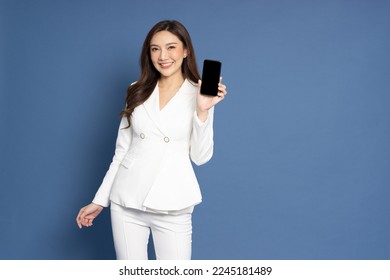 Portrait of Asian business woman showing or presenting mobile phone application isolated over blue background, Asia Thai model
