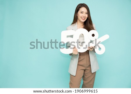 Portrait of Asian business woman showing and holding 50% number or Fifty percent isolated over light green background