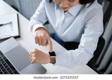 Portrait of  Asian Business woman watching at wristwatch while working on laptop computer in office. watching the time 
working new start up project. - Powered by Shutterstock