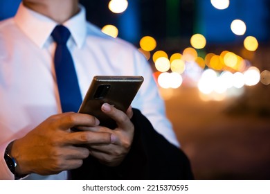 Portrait Asian Businessman Typing An Sms Message Via Smartphone After Work Near Office At Night City Street, Bokeh Lights, Young Man Walking And Chatting With Friends At Social Networks Outdoor