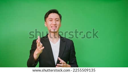  portrait asian businessman wear black suit hosting tv show or advertisement in front of green screen