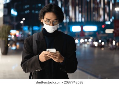 Portrait of an Asian businessman wearing a mask, in the street at night - Powered by Shutterstock