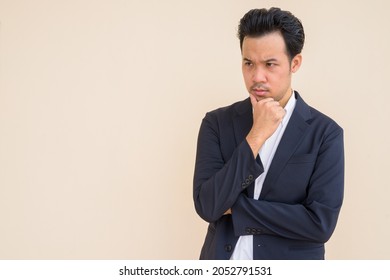 Portrait Of Asian Businessman Wearing Suit Outdoors Against Plain Background