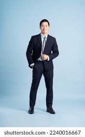 portrait of asian businessman wearing suit on blue background - Shutterstock ID 2240016667
