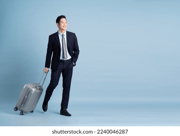 Portrait of Asian businessman wearing a suit and pulling a suitcase - Powered by Shutterstock