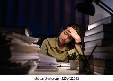 Portrait of Asian Businesswoman sitting and working hard at with front of computer and lots of documents on the table in workplace at late with serious action, Work hard and too late concept - Shutterstock ID 2256422063