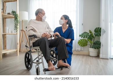 Portrait Of Asian Caregiver Nurse Take Care Senior Male On Wheelchair. Attractive Specialist Carer Women Wear Face Mask, Support Elderly Grandfather At Nursing Home Care And Smile, Look At Each Other.