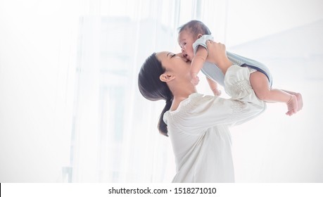 Portrait of asian or caucasian mother lifting and playing with newborn baby, baby talking to mother day. Health care family love together. Asian girl lifestyle. Asia mother's day concept 
