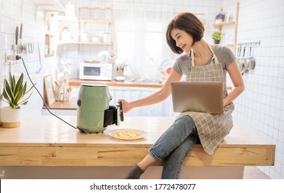 Portrait Of Asian Chef Girl Cooking Potato Fried By Air Fryer Machine In Kitchen Home. New Normal Work At Home Lifestyle. Technology Eco Friendly Home Smart Device, Asian Housewife Concept