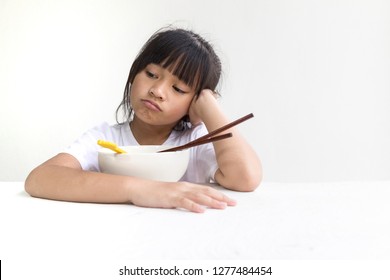 Portrait Of Asian Child Girl Refuse To Eat Food Or Food Bored, Child Anorexia And White Wooden Table With White Background.