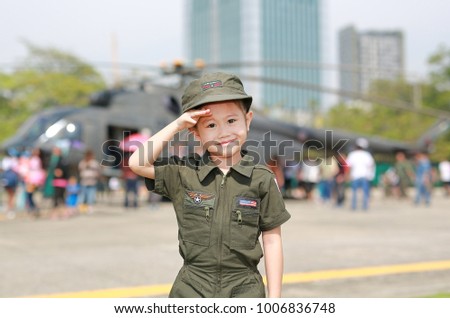 Portrait of asian child girl wearing airforce pilot suit against blur helicopter background.