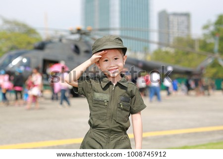 Portrait of asian child girl wearing airforce pilot suit against blur helicopter background.
