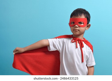 Portrait of Asian child in Superhero's costume isolated on blue background. Success and winner concept - Powered by Shutterstock