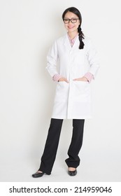 Portrait Of Asian Chinese Girl In White Lab Uniform Smiling, Full Body Standing On Plain Background.