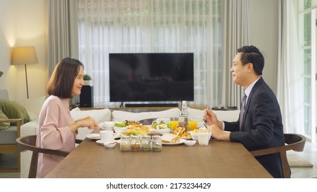 Portrait Of Asian Couple Eating Dinner Or Breakfast Meal, Food On Table At Home With Blank Screen Tv. People Family Activity. People Lifestyle Celebration Anniversary