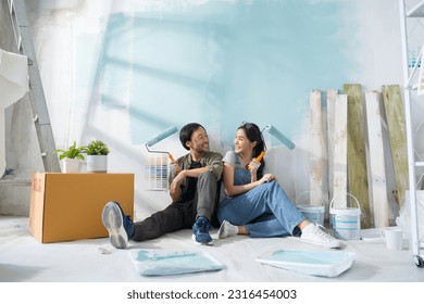 Portrait Asian couple repairing and painting the wall with blue paint using a roller during renovation in their new apartment. - Powered by Shutterstock