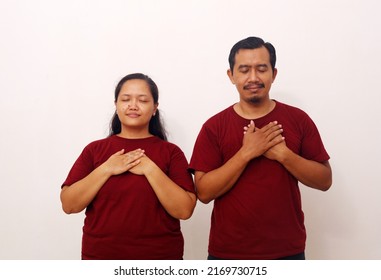 Portrait Of Asian Couple Standing While Holding Their Chest. They Feel Relieved. Isolated On White