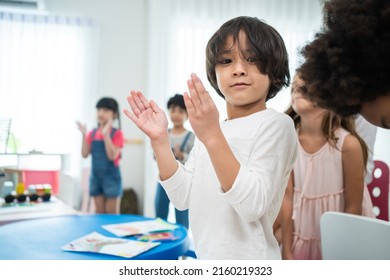 Portrait Of Asian Cute Child Boy Standing Clapping Hands In Classroom. Student Young Little Kid Boy Applaud To Answer Questions In Schoolroom Enjoy To Study With Smiling And Look At Camera At School.