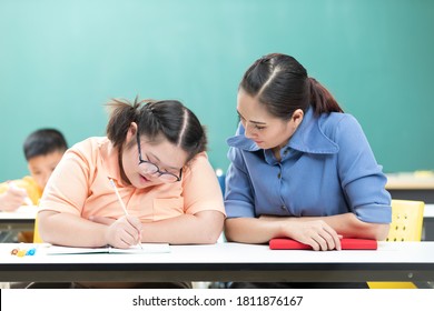 Portrait Asian Disabled Child Or Autism Child Writing A Book And Woman Teacher Helping In Classroom