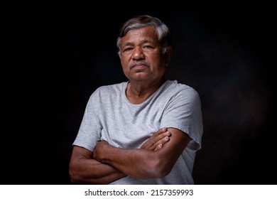 Portrait Of Asian Elderly Man Alone Looking At Camera In Studio On Dark Background, Wrinkled Skin, Gray Hair, 60+ Years Old.