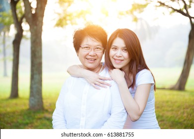 Portrait Of Asian Elderly Mother And Daughter, Senior Adult Woman And Grown Child. Outdoors Family At Nature Park With Beautiful Sun Flare.