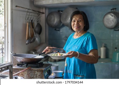 Portrait Of Asian Elderly Woman Happy Smiling Cooking Thai Food In Kitchen At Home. Grandmother Preparing Dinner For The Family