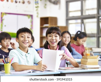 Portrait Of Asian Elementary School Students In Classroom Looking At Camera Smiling.