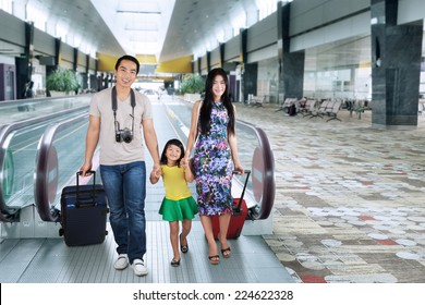 Portrait Of Asian Family Carrying Luggage And Walking In The Airport Hall For Holiday