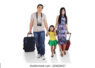 Portrait Of Asian Family Walking In Studio While Carrying Luggage For Holiday