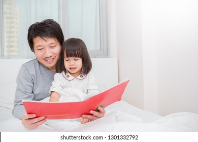 Portrait Of Asian Father Holding Story Book Teaching Daughter Little Girl In Bedroom. Teacher Home School Bed Time Story Learn, Education Knowledge Happy Family Love Together Single Dad Father’s Day.