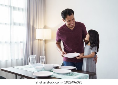 portrait of asian Father and small daughter preparing dining table for dinner - Powered by Shutterstock