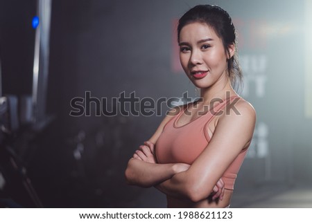 Portrait of Asian female athlete wearing sportswear looking at camera in fitness gym